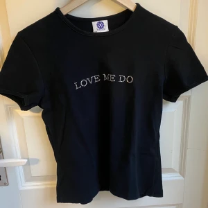 Croppad t-shirt - Skitsnygg croppad t-shirt med texten ”Love me do” skrivit i strass. Storlek L men sitter mer som ca en S. Ett litet hål i armhålan, men det går lätt att laga. 