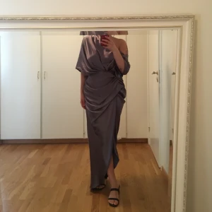 Asos silver långklänning  - Superfin draperad långklänning, elegant, med öppen rygg och slits i mitten så lite av benen syns. Använde denna en gång på ett bröllop förra sommaren och har nu kemtvättat den:) storlek står 40 men passar dock en 38a eftersom den är liten i storleken. Skriv om ni har några frågor!