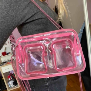  - Säljer min mycket sparsamt använda NuNoo väska. Ljusrosa och genomskinlig. Livar upp vilken outfit som helst!! Kan mötas i Stockholm eller fraktas. Buda