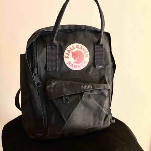  - Fjällräven kånken mini i färgen Navy. Dragkedjan till främre fickan är sönder. Den blåa färgen kommer inte fram så bra på bild, är även lite solblekt. Hämtas på Hisingen, Göteborg.     