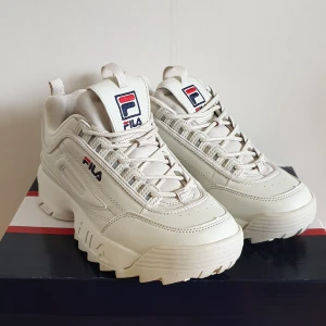 NYA Fila Disruptor Turtledove strl 40 - Helt nya Fila Disruptor i färgen turtledove säljes då de är för små för mig. De är storlek 40/UK 6.5 men väldigt små i storleken så skulle snarare säga 38,5-39. Nypris 1195 kr. Katt har funnits i hemmet 🐱 Pris kan diskuteras, PM för frakt!