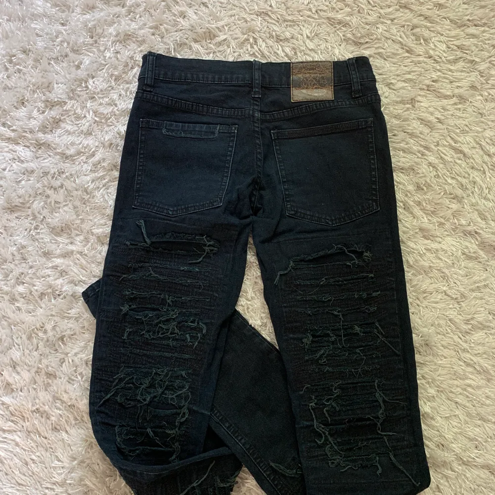 Snygga mörkblå tighta jeans med slitningar längs benen både bak och fram. Jeans & Byxor.