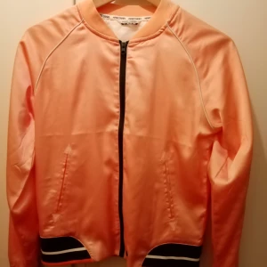 Kaaritraa jacka!  -  Kaaritraa jacka i snygg rosa/aprikos färg, glansig. Helt oanvänd. 