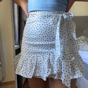 Prickig kjol - Säljer en söt kjol från Shein. Vit med svarta prickar, volang längst ner och ett snöre i midjan som går att snyta som man vill:) Otroligt fin och är så ledsen att jag ska sälja den men tyvärr så har den blivit för kort. Kvaliten är bra. Frakt tillkommer!!