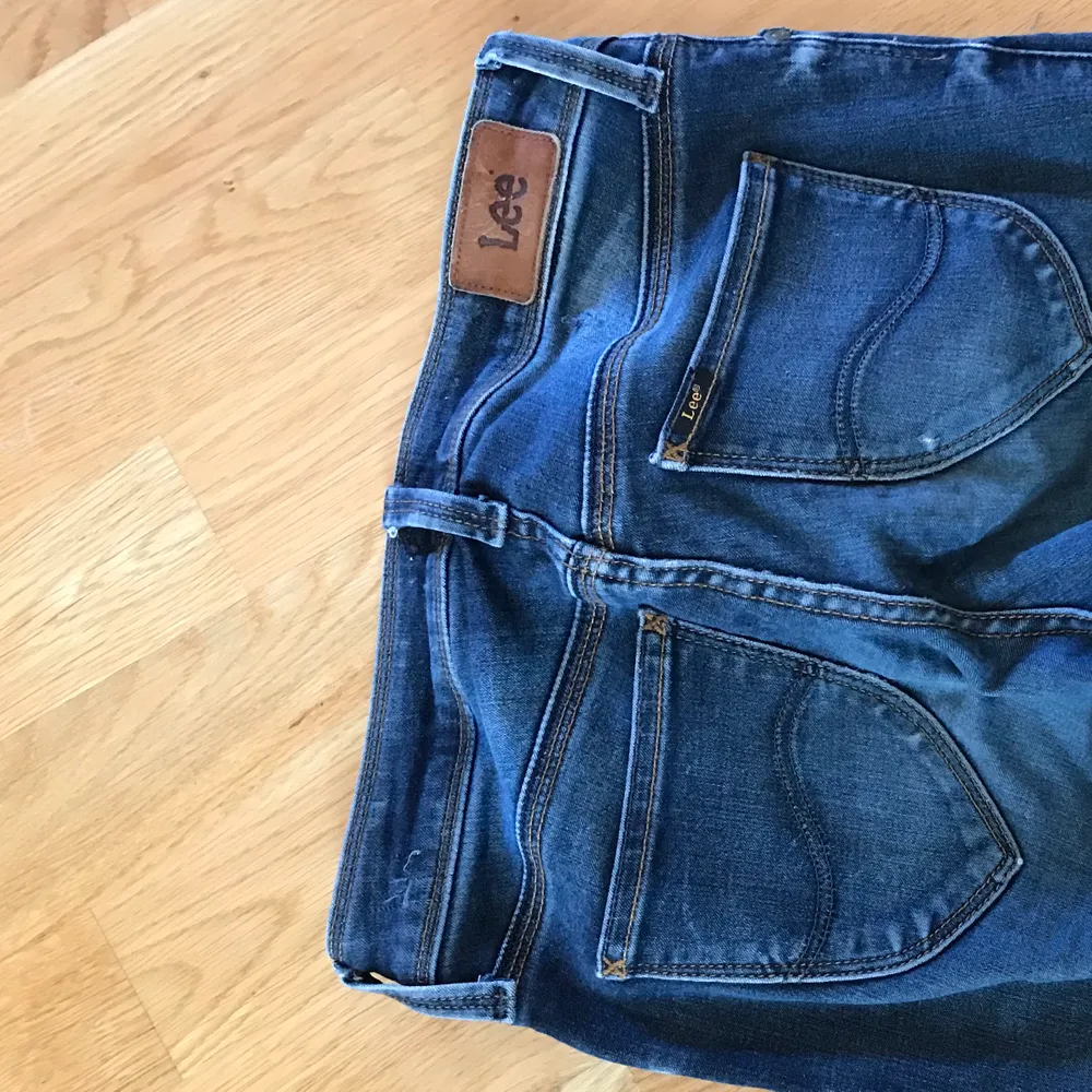 Ett par mörkblå jeans från Lee som använts en del och har någon slitning där bak och något hål på ena knäet. Men de är fortfarande i väldigt fint skick!. Jeans & Byxor.