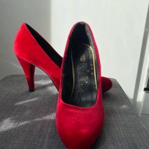 Röda pumps i sammet  - Röda pumps i sammet. Storlek 40. Endast använda 1 gång. Någon liten fläck på sidan av skorna.
