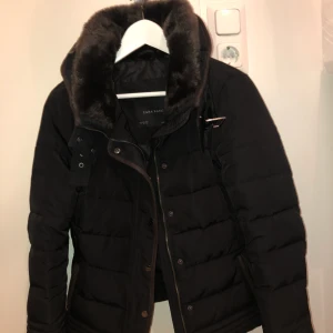  - Svart jacka med bruna detaljer och fuskpäls i kragen. Flitigt men försiktigt använd och därför i väldigt fint skick. Köparen står för frakten. 