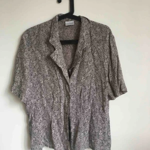  - Blommig grå second hand skjorta. En knapp saknas, se bild nr 3. Annars i bra skick. 