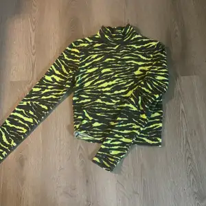 Långärmad tröja med liten krage och tiger mönster i lime grön och svart. Använd ett par gånger men fortfarande bra skick. 😄 frakt diskuteras privat 