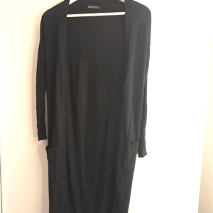  - Fin lång svart kofta från Behrska. Den går nedanför knäna och har två fickor. Bra skick och lite använd. 