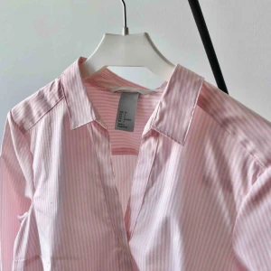  - En snygg rosa-randig skjorta från H&M. Knappt använd. (Frakt tillkommer om den ska skickas)