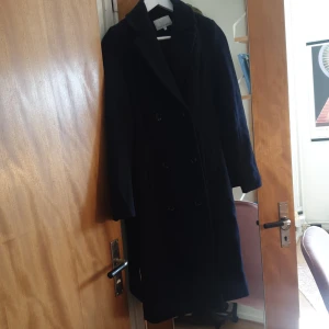 Ullkappa med dubbeltknäppning  - En varm och snyggt sittande julklappar med dubbeltknäppning och bälte. Marinblåfärg. Ljusare än bildena. Köpt på zalando. Säljer för att jag har en ny julklappar och får inte plats hemma med denna. Kan mötas i Gbg eller frakta.