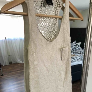  - Vitt linne med spets och spetsdetalj i ryggen. Använd få gånger.