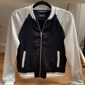 Snygg jacka  - Snygg tunn jacka i grått/marinblått. Nyskick, aldrig använd. Storlek M men passar även S. 