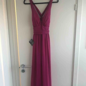  - Mörkrosa klänning med korsad rygg.. sitter snyggt på och faller fint ... Aldrig använd, etiketten är kvar! 