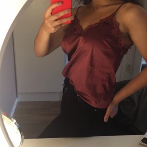 Rött silkeslinne - Rött linne i silkeliknade material med smala axelband och fina mönstrade detaljer. Köpt för ca 250 på bikbok. Använd 2-3 gånger max. JAG STÅR EJ FÖR FRAKTEN!!!