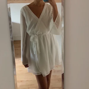 Vit klänning med band i midjan - Endast använd en gång. Fraktkostnaden är inkl i priset.