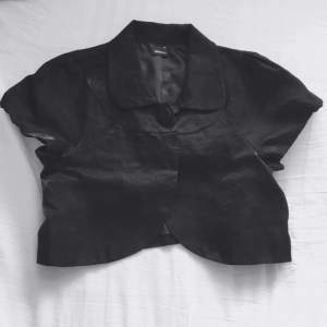 En söt liten kortärmad svart jacka i skimrande tyg❤️ passar jättebra till en fin klänning på kvällen 👌🏾