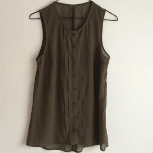  - Mörkgrönt transparent linne från vila. 
Bortklippt lapp och en knapp saknas. 
Använt en gång.