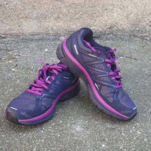  - Salomon sneakers stl 39 1/3, använda utomhus en gång! Lila och med snygga skosnören med reflex på. Även reflex på själva skon. Den perfekta löparskon. Lite små i storleken så är mer en stl 38. Frakten ingår i priset! 