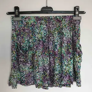 En färgsprakande blommig kjol i mjukismaterial med två fickor på framsidan. 