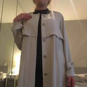  - Fin ljusbeige tunn vårkappa! Ganska lång, når ca ner till vaden.  Pris kan diskuteras!