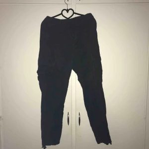  - Black cargo pants, köpta här på Plick och insydda så de sitter ordentligt i midian. Går att spänna vid anklarna  Skick:använda i gott skick