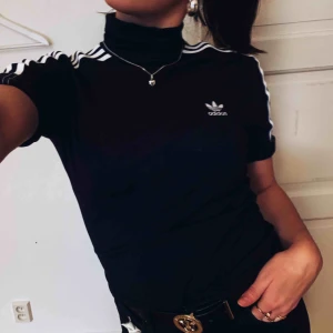  - Svart t-shirt med polokrage från adidas. Väldigt snygg och bekväm. Ärmarna går att förkorta om man vill likt bilden. Fler bilder kan skickas och frakt ingår ej. 