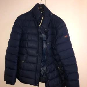 Tommy Hilfiger Dunjacka - Tommy Hilfiger Dunjacka storlek M i mörkblå. Använd. Passformen är lagom slim och jackan passar både till höst och vinter då den är varm.