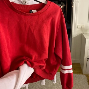 Röd tröja från H&M - Röd långärmad tjocktröja med vita sträck på ärmarna 