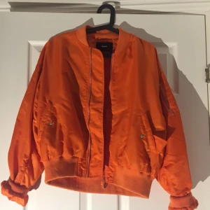  - Riktigt härlig orange oversized bomberjacka! Köpt här på plick men var inte min storlek så jag säljer vidare! Använt skick och saknas en knapp som syns på bild nr 2. Man kan knäppa fast en egen knapp om man vill. 