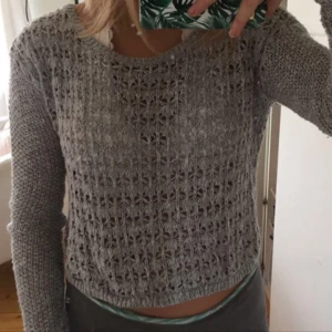  - Grå stickad tröja med lite silver trådar (bild 3). Tröjan kommer från hollister och är i storlek XS. Halsringningen är stor och man kan därför låta den falla över axeln (bild 2).