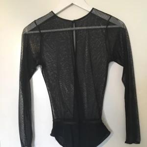  - Genomskinlig svart body med prickmönster. Knäppes bak i ryggen. Knappt använd!