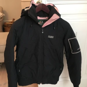  - Peak Performance Hipe Skidjacka i dun. Svart med rosa detaljer. I väldigt gott skick och varm, nypris 2500kr. 