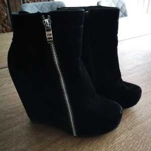  - Snygga kilklack boots i svart mocka med en dragkedja detalj.  Använda fåtal gånger. 13cm klack varav 2cm platå Jag har swish  Köparen står för frakten. 