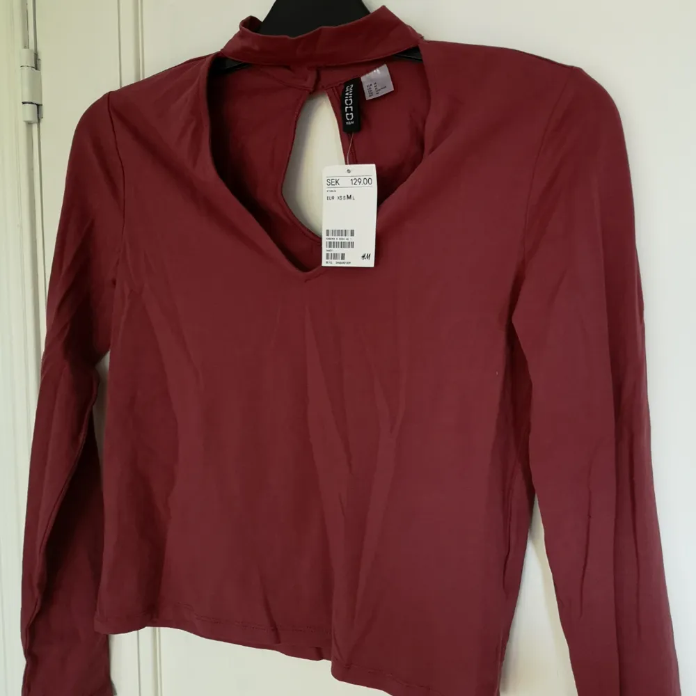 En mörkröd fin tröja med öppning vid brösten och liten öppning vid ryggen. Även en 