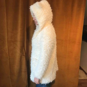  - Helt ny jacka/kofta i fuskpäls. Söta öron på luvan. Jättegosig och fodrad. lång modell med fickor fram. Finns i Nacka. Köparen står för ev. frakt 