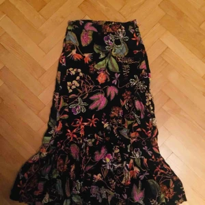  - Poppis kjol till salu! Köpte fel storlek så har haft den en gång bara. Volanger och vackert tryck! Figurnära.