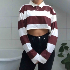 - En cropped rugby skjorta i burgundy- och vitrandigt mönster. Cool som danströja eller till vardags! Passar bra med ett pr högmidjade jeans!