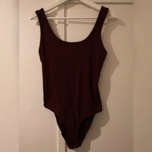  - Vinröd body med djup rygg, aldrig använd! Köparen står för frakt. 