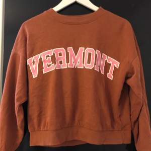 En rosa brun tröja från gina tricot. På framsidan står det ”Vermont”