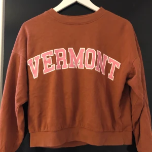 Tröja  - En rosa brun tröja från gina tricot. På framsidan står det ”Vermont”