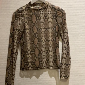 Meshtopp med ormskinnsmönster  - Meshtopp med ormskinnsmönster från Nelly Trend i storlek S. Aldrig använd och i superfint skick!!