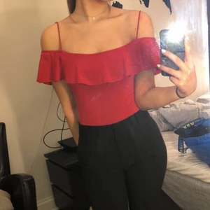 Röd body - Så fin röd bodysuit med volang”kant”. Man kan ha den på lite olika sätt vid armarna.  Strl s men passar xs oxå