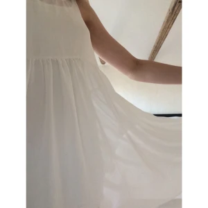  - Vit sommarklänning i transparent och fladdrigt tyg med vackert fall.