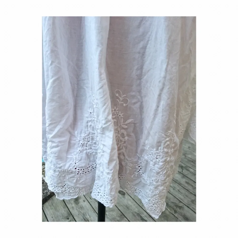 Klänning/tunika i vitt med långa vida ärmar. Virkade/broderade detaljer längst ut på ärmarna och längs med klänningens kant . Klänningar.