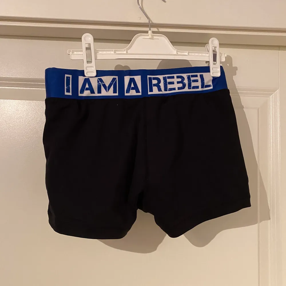 Svart/blå shorts från Rebel Athletic med texten ”I am a rebel” på baksidan.. Shorts.