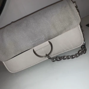 Väska - Axelremsväska ifrån Nelly (fyra fack och långt band finns i) Limmet har släppt lite så övertyget är löst men går nog att fästa på nåt sätt! Finns i centrala Uddevalla annars står köparen för frakt.