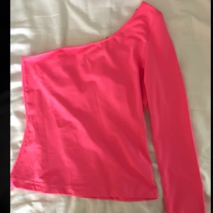 Fest topp - Super cool one shoulder tröja i neon rosa! Finns ingen mer perfekt fest topp💓🍸 endast använd 1 gång då den inte riktigt är min stil😢 säljer för 85kr med gratis frakt!!!