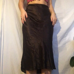 Brun kjol - Brun kjol i lite skimrigt material. Gott second hand skick. Materialet liknar siden. Visas på en storlek m. Skriv privat vid intresse. Köpare betalar frakt. Högsta bud 200kr